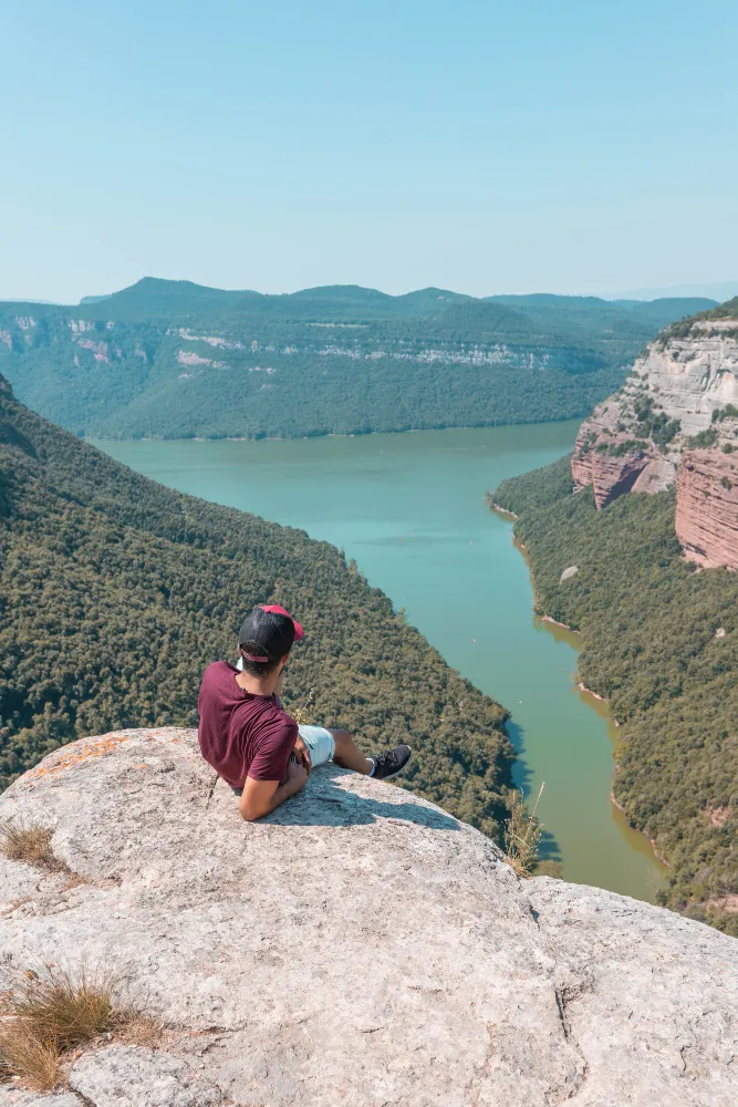 Ein Mann sitzt auf einem Felsen und geniesst die Aussicht auf den Fluss unter ihm